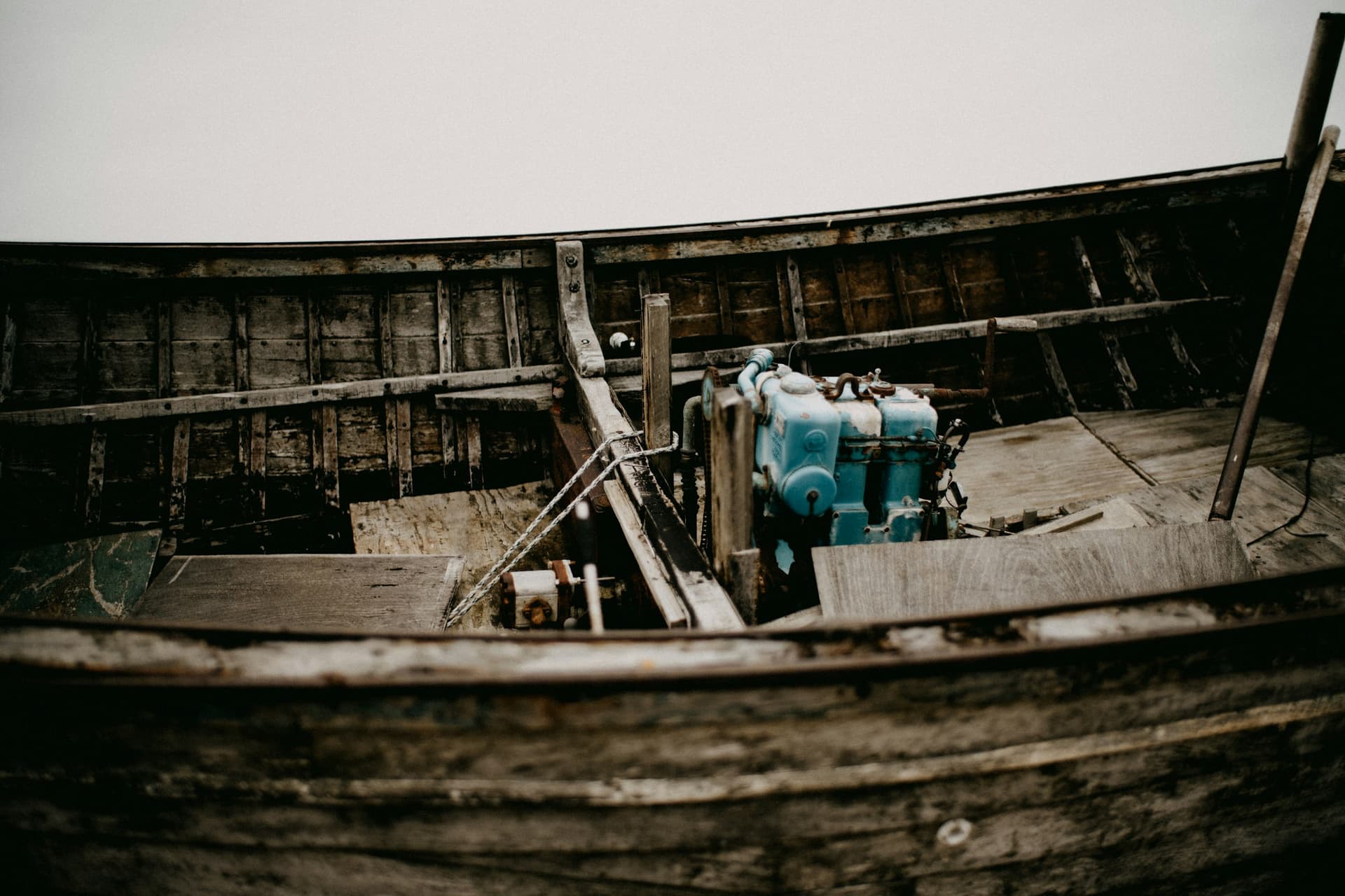 A weathered open wooden boat with a small blue inboard engine mounted among its floorboards.